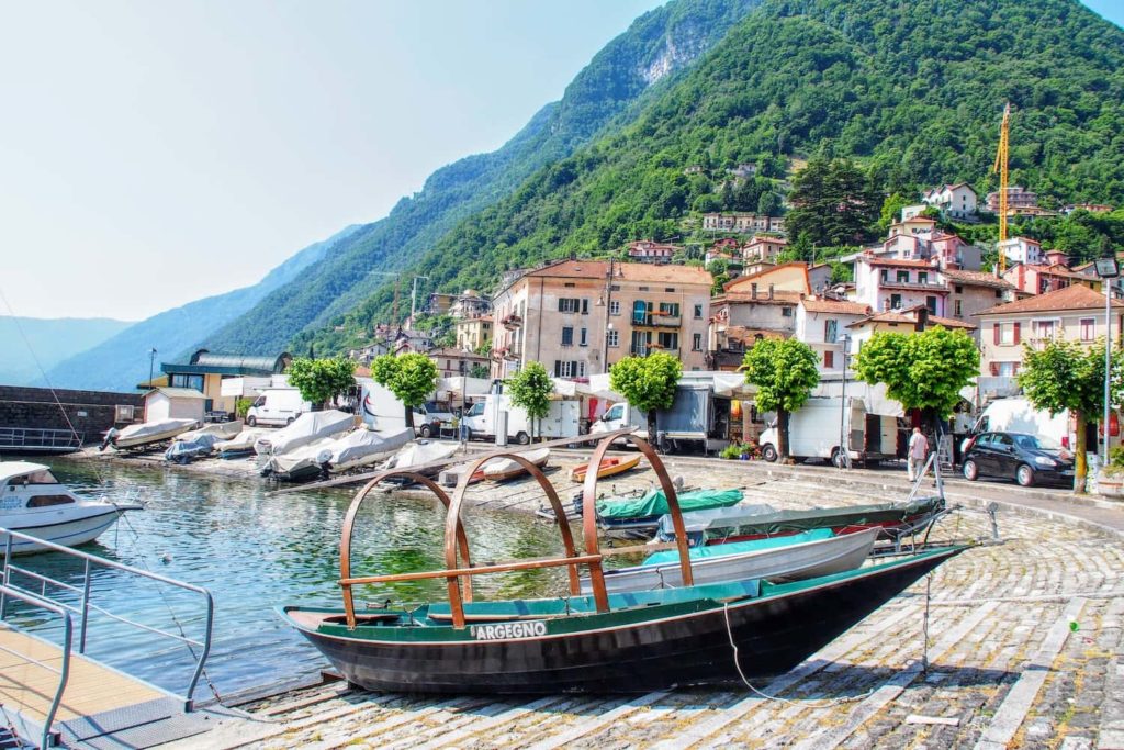 A boat rests in Argegno's small harbour while the markets takes place in the background